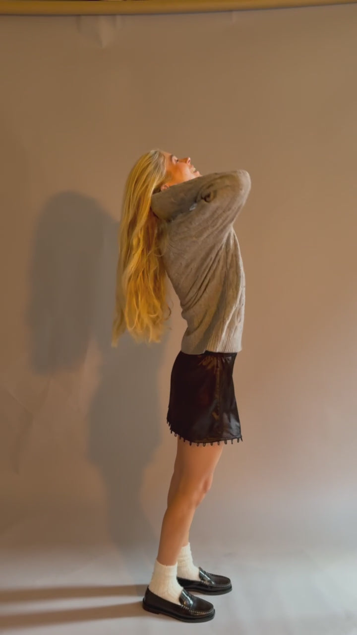 Young woman wearing a grey sweater and the short black STOW Apparel Gemini skirt